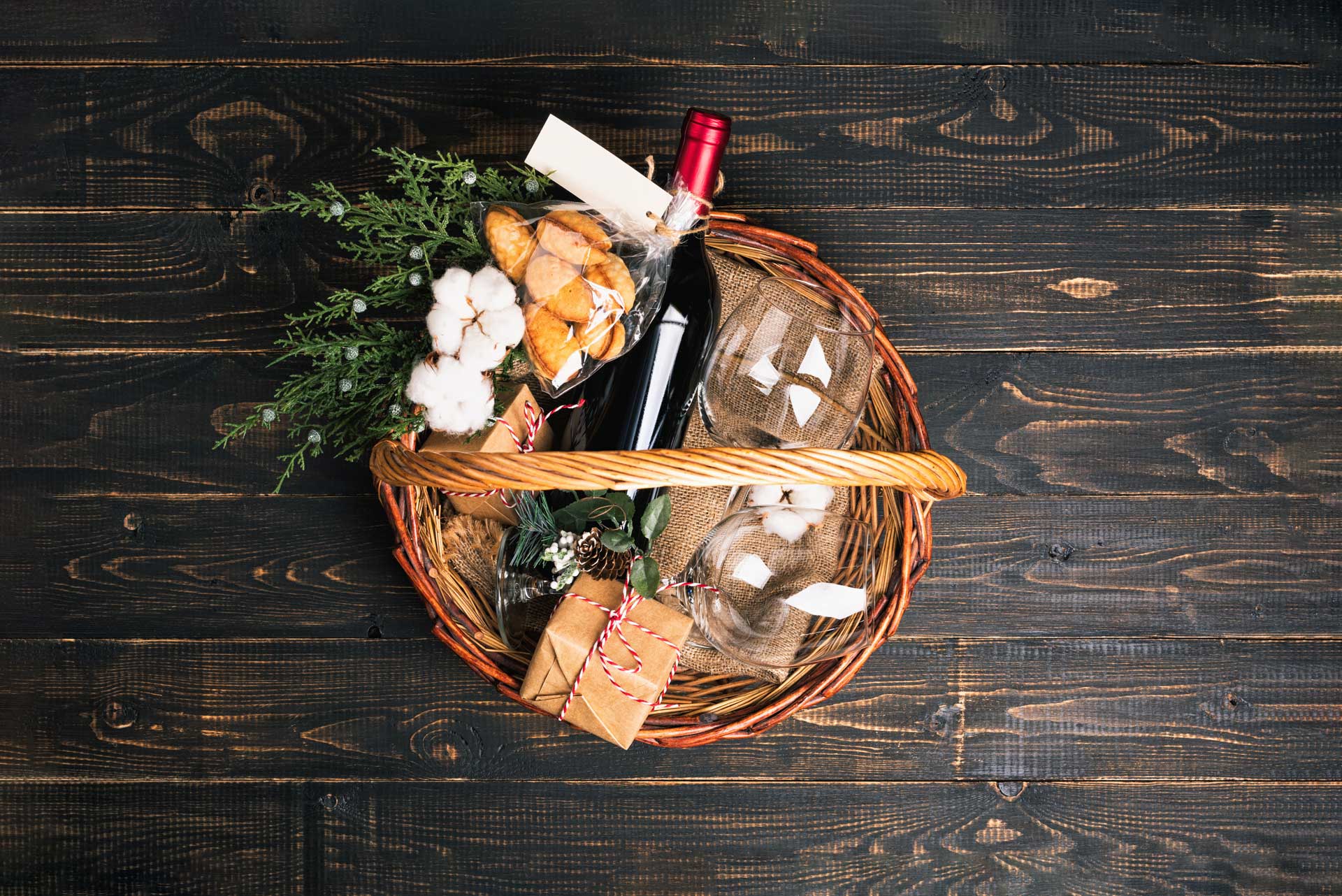 wicker gift basked with various items including a model of wine and glasses